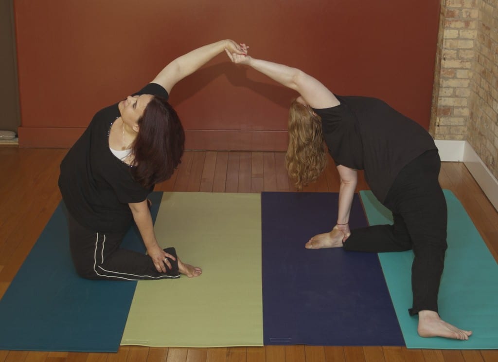 Courtney Stocker with Katie Cook doing gate pose (parighasana)